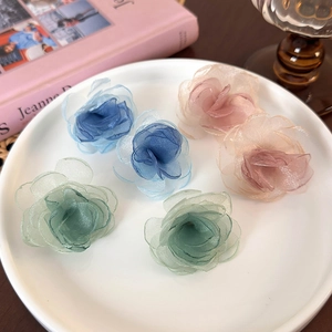 Detail of delicate handmade organza fabric flower earrings in blue, pink, and green