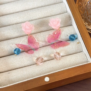 Detail of pink crystal butterfly earrings with resin rose and beaded tassels