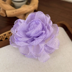 Gros plan d'une pince à cheveux fleur en gaze violette avec des pétales en tulle multicouches