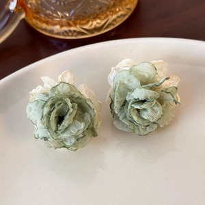 Detail of multi-layered mesh fabric flower earrings in sage green and cream colors