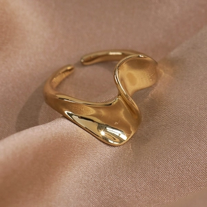 Detailed macro shot of an irregular wave golden ring on champagne silk fabric background