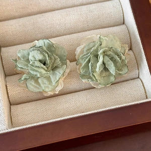 Close-up of lightweight light green mesh flower earrings with layered fabric petals