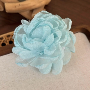 Vue macro d'une pince à cheveux fleurie en organza bleu clair aux pétales élégants