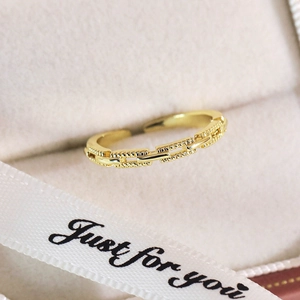 Détail d'une bague papillon dorée avec texture chaîne dans un coffret cadeau