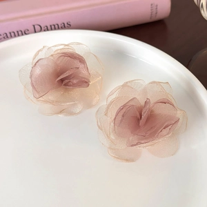Detailed close-up of 3D layered pink mesh flower earrings on a white ceramic plate