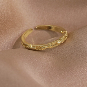 Gros plan d'une bague dorée ajustable avec relief texturé sur satin champagne