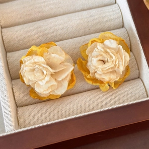 Close-up of layered yellow mesh flower earrings with detailed fabric petal textures