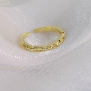 Gros plan d'une bague dorée texturée sur un tissu en soie blanche douce