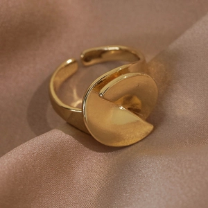Close-up of golden irregular geometric twist ring on champagne satin fabric