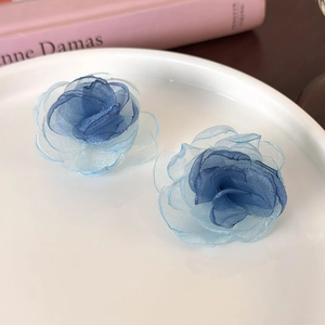 Detailed close-up of blue 3D gauze rose stud earrings on a minimalist white ceramic plate
