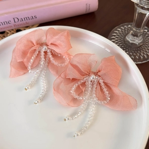 Detailed view of pink chiffon bow earrings with crystal tassels and white pearl center