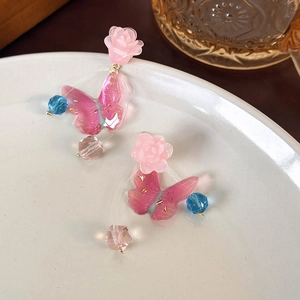 Detail of pink resin flower and crystal butterfly earrings with soft blue beads