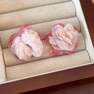 Detailed macro view of 3D layered pink gradient tulle flower earrings in a jewelry box