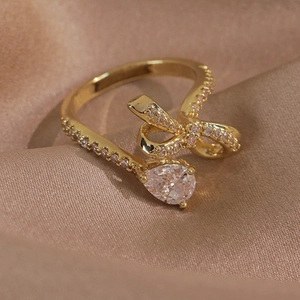 Gros plan d'une bague papillon dorée avec zircone poire sur du satin de couleur champagne