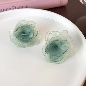 Detail of light green layered mesh flower earrings on a white ceramic tray