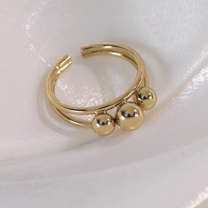 Detailed macro view of a gold double-layer open ring featuring three polished metallic beads
