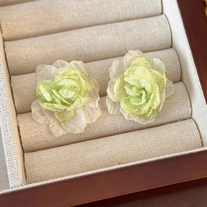 Close-up of handmade floral mesh earrings featuring layers of light green organza fabric