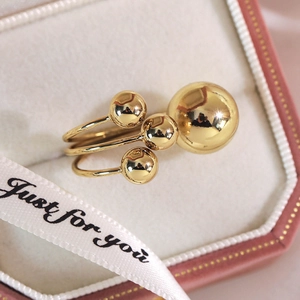 Close-up of golden multi-ball ring on white silk lining inside a pink gift box
