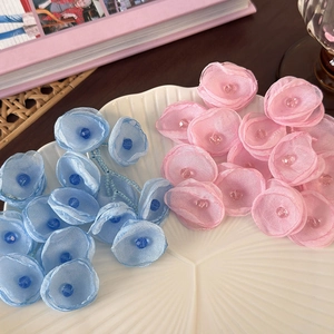 Floral chiffon fabric earrings with crystal beads in pink and blue on a shell tray