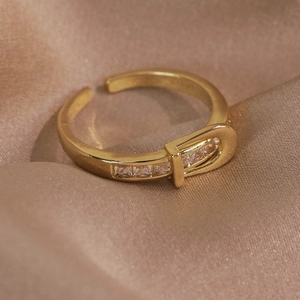 Vue macro d'une bague boucle dorée avec zircons cubiques sur fond de soie champagne
