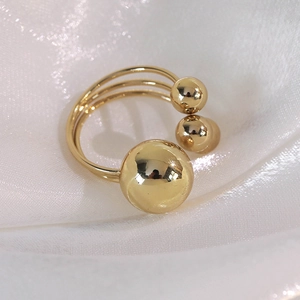 Detailed macro of gold layered ring with three polished metal spheres on silk background