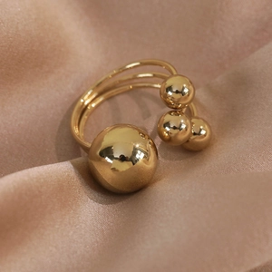 Macro detail of triple-layered golden ring with polished sphere accents on silk fabric