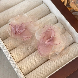 Detail shot of delicate pink mesh flower earrings with layered petals on jewelry box