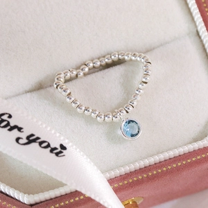 Gros plan d'une bague perlée en argent avec pierre bleue dans un écrin cadeau rose