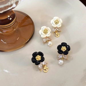 Close-up of camellia enamel earrings with pearls, zircon, and number 5 pendants