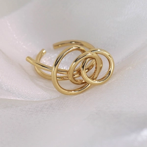 Detail of a minimalist gold layered open ring on soft white fabric background