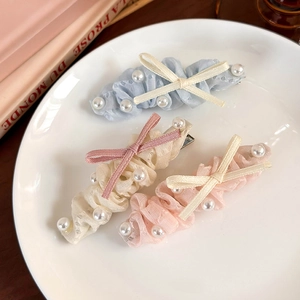 Trois élégantes barrettes à nœuds en dentelle et perles sur une assiette en céramique