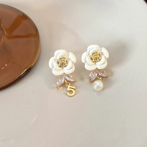 Detail view of asymmetric camellia earrings with pearl and number five charm