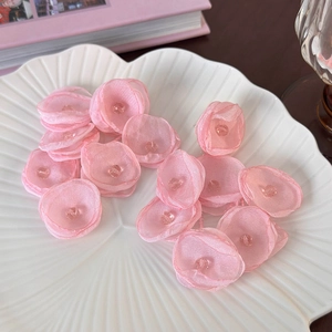 Detail of pink organza fabric flowers with crystal beads on a white ceramic plate