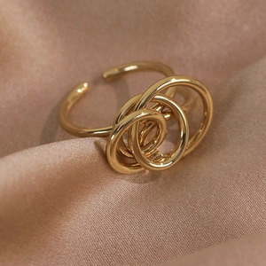 Detailed view of intertwined geometric gold ring on champagne satin background