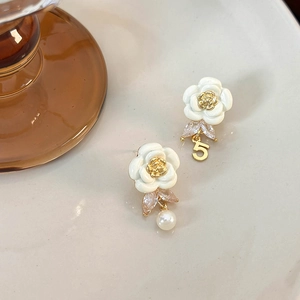 Detailed close-up of French camellia earrings with pearl, zircon, and number 5 charm