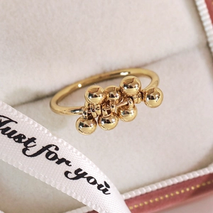 Macro shot of gold-plated ring featuring sliding polished metal beads on a gift ribbon