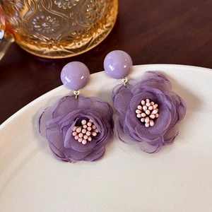 Close-up of purple mesh flower earrings with pink stamen and elegant gold accents