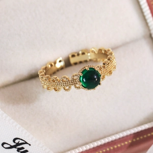 Gros plan détaillé d'une bague dorée vintage avec une pierre précieuse vert émeraude
