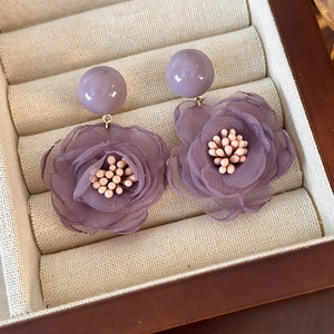Detailed macro view of purple mesh flower earrings with elegant polished beads and petals