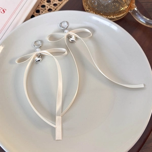 Dettaglio di orecchini a cerchio con perle bianche e lunghi nastri di seta beige