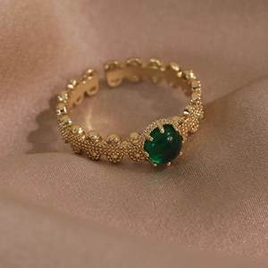 Vue détaillée d'une bague vintage en or avec pierre verte sur tissu en satin