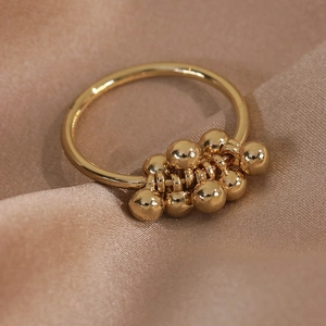 Detail of minimalist gold ring with polished beads on champagne silk background