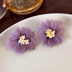 Detailed macro shot of purple mesh flower earrings with yellow resin stamen in a ceramic tray