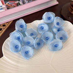 Detailed macro view of light blue fabric flower earrings with crystal beaded center