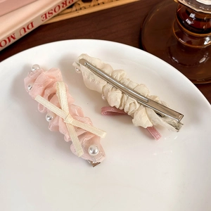 Détails de barrettes à perles avec nœud rose et dentelle blanche sur une assiette en céramique