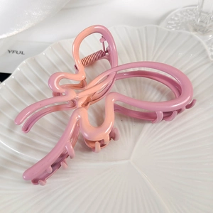 Détail d'une pince à cheveux papillon mate avec un dégradé de rose et d'orange doux