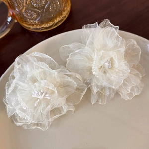 Close-up of elegant white tulle floral earrings with delicate layered organza petals