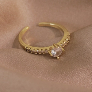 Macro de la bague ajustable dorée avec zircon rond sur un tissu en soie de couleur champagne