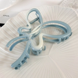 Détail d'une pince à cheveux papillon bleu dégradé avec finition mate sur une assiette