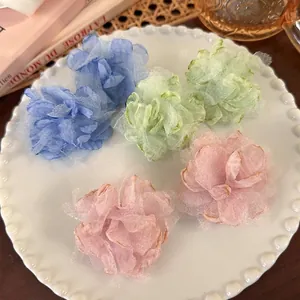 Chic layered fabric flower earrings in pastel colors on a decorative ceramic tray